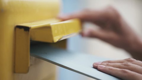 Woman is sending a blue letter into a yellow letterbox. 4K