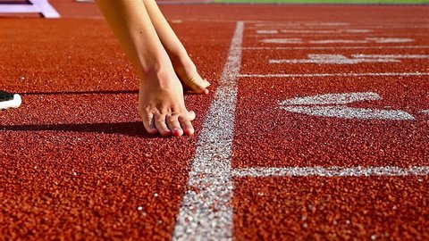 Track runner woman putting her hands at starting line, slow motion