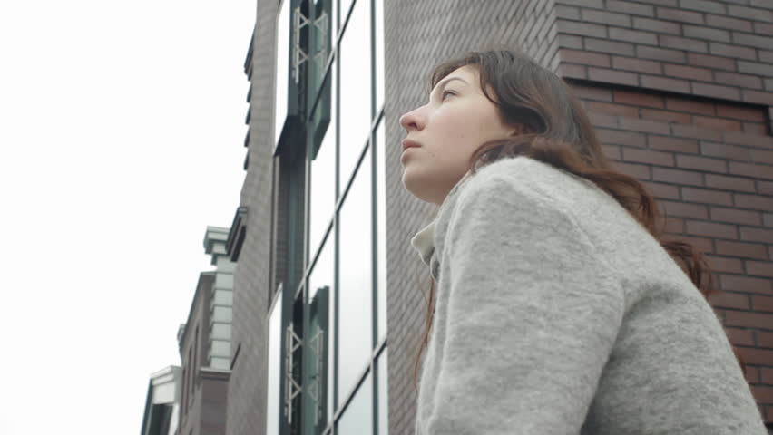 Beautiful young girl sitting at the building and dreaming  