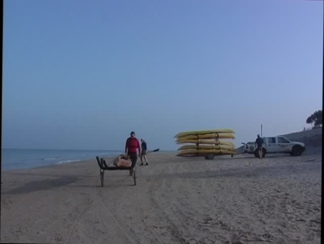A man pulls canoe to the sea