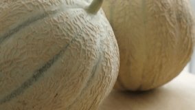 Cucurbitaceae family melopepo fruit pair on kitchen table 4K 2160p 30fps UltraHD tilting footage - Slow tilt over food background made of two tasty melons 3840X2160 UHD video