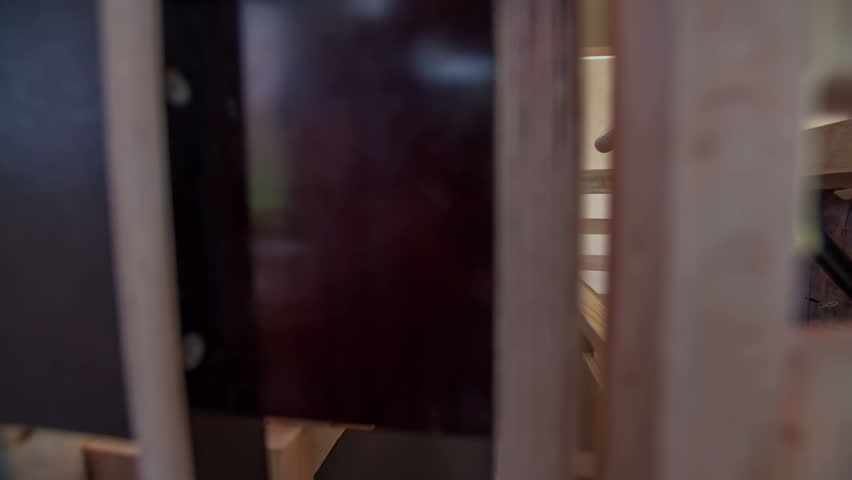 A man is bringing one part of the seats and he is building the inside of the wooden car that he has designed. Close-up shot.