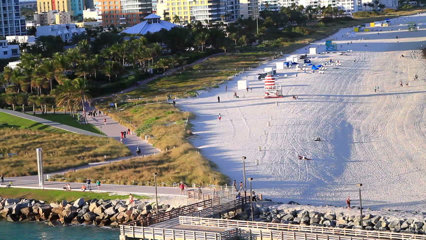 miami beachline with a pier in the water at sunset