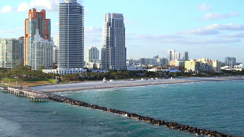 miami beachline with a pier in the water at sunset