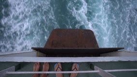 Video of couple's feet on the boat and sea wave behind large cruise ship. Hazy due to pollution smoke from smoke stacks and engine. Horizon in distance