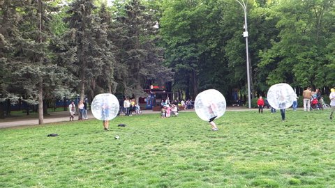 KRASNODAR, RUSSIA – MAY, 1, 2016: Young people are enjoy playing in zorb in the big transparent plastic ball on the grass