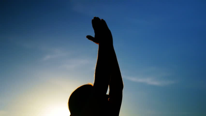 Woman performing yoga on the beach at dusk
