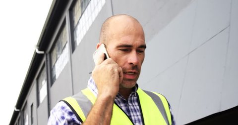 Welder talking on phone while walking outside workshop