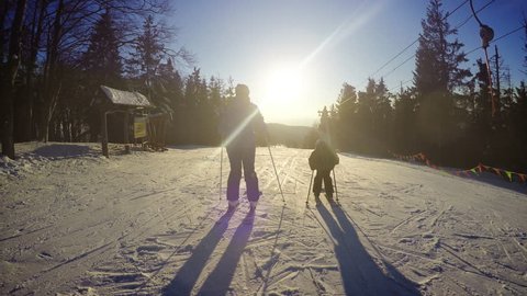 4K footage of mother and son skiing down from a slope on a sunny afternoon
