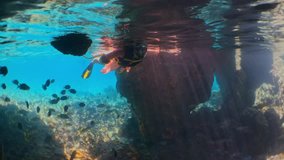 Woman snorkeling among fish and corals. Exuma, Bahamas.
