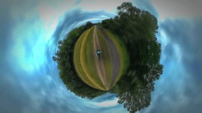 Tiny Little Planet 360 Degree Timelapse. Tourist is Riding a Bicycle by Woodland in Opole. Along River, Lake, Sea and Holding Camera on a Stick, Filming. Backpacker is Traveling in Warm Autumn Day.