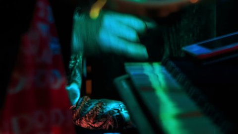 closeup woman hands play tambourine in night bar under flashes of colourful lights