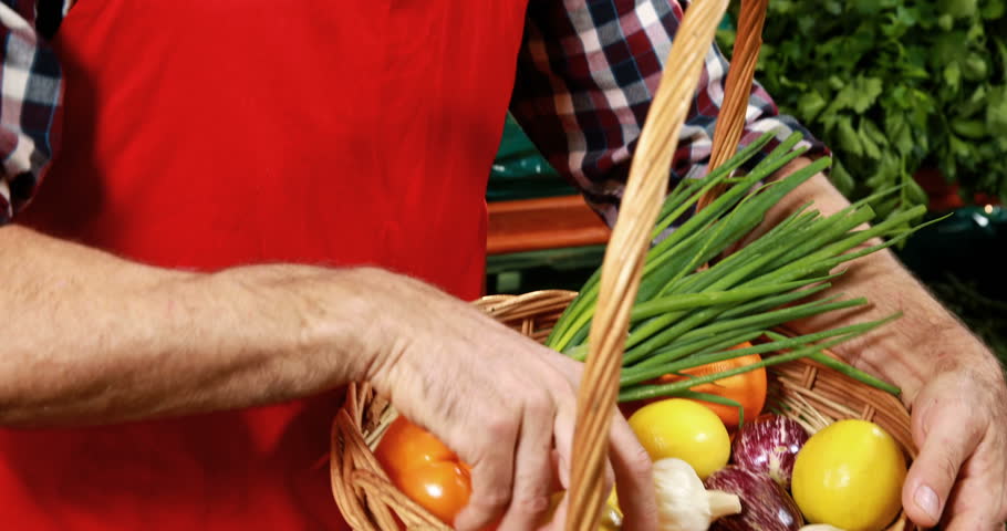 Smiling male staff arranging fresh vegetables in basket at supermarket 4k