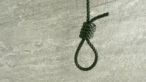 Noose hanging in front of stone wall film clip. Symbol of death, capital punishment and execution.