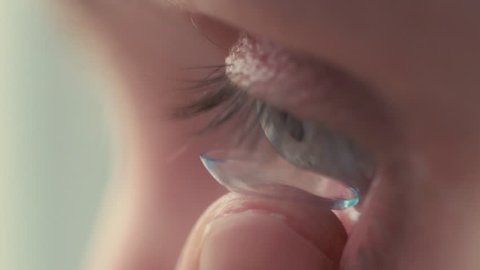 Young handsome man putting contact lens in her eye close up.