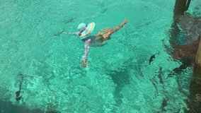Woman swims among nurse sharks and exotic fish. Compass cay, Bahamas