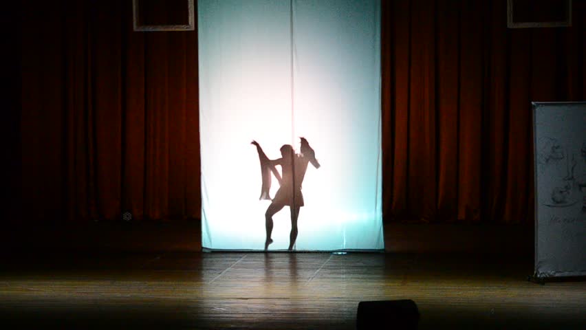 The dancer dances behind a white background, dance of a shadow.