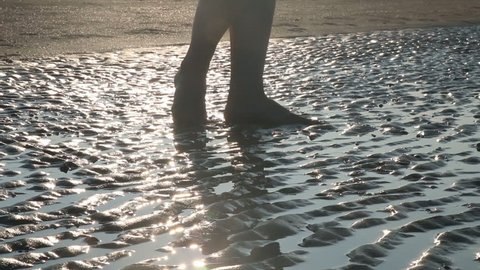 Young Woman Dancing on wet sand on sea beach against the sun