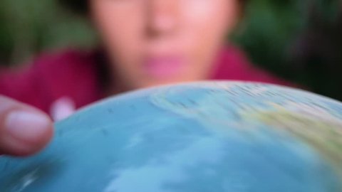 Hispanic woman choosing her next travel site on a spinning globe