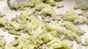 Stir frying chopped yellow onion in hot fry pan, macro slow motion
