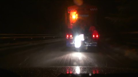 Snowblower with rotating lights on the road at night. Drive on the road at night during the fall of heavy snow