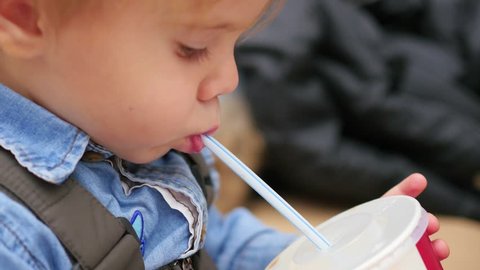 a child drinks from a straw carbonated drink closeup