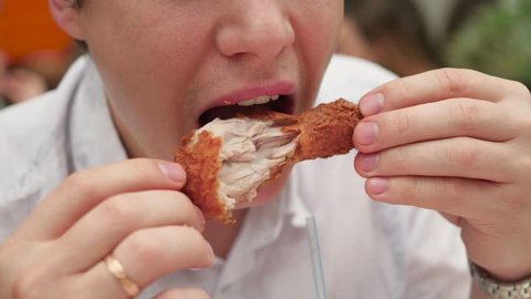 guy eats fried chicken in a fast food restaurant closeup
