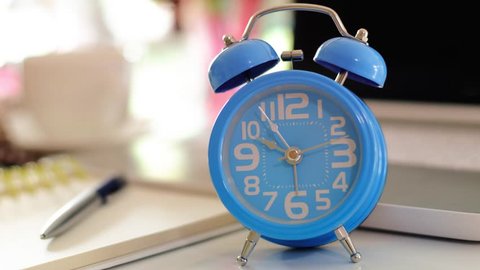Blue classical twin bell alarm clock on working table, time lapse 