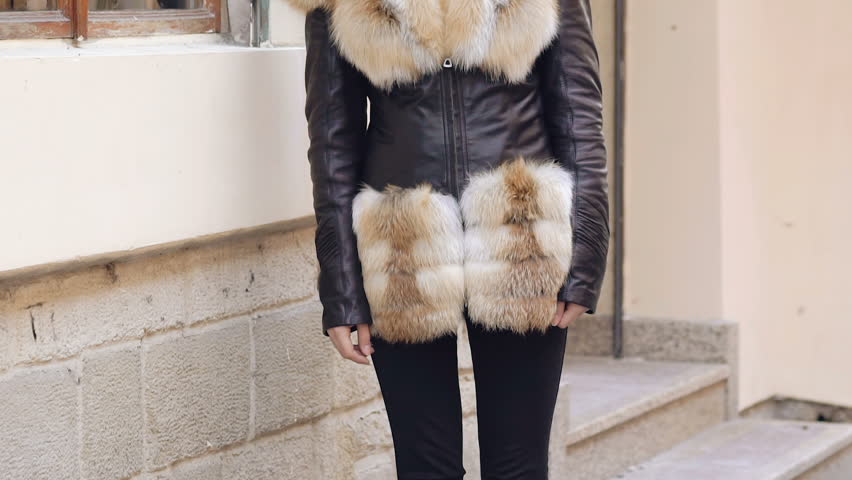 Young cute girl posing in furry jacket on the street. Slow motion