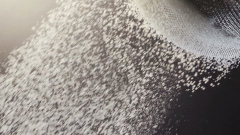 Flour falling through a metal sieve. close up