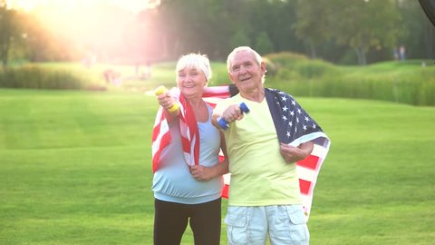 Couple of seniors with dumbbells. People with USA flag. Stay true to family values. Health and patriotism.