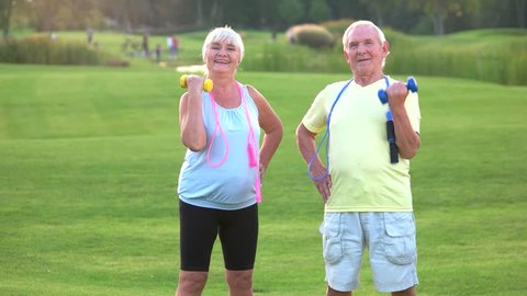 Elderly couple with dumbbells. People doing exercise and smiling. Sportsmen never get old. Mood and motivation.