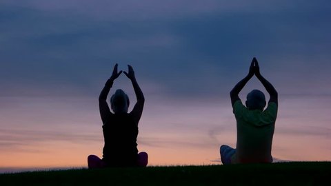 Couple doing yoga. People on sunset sky background. Strive to harmony. Way to peace and balance.