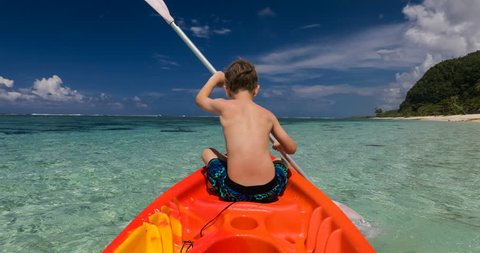 Young shirtless caucasian boy kayaking at tropical sea