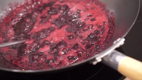 Boiling berries in a pan to make fruit jam, boiling red sauce