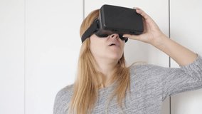 Blonde woman in white space trying virtual reality glasses 4K 2160p 30fps UltraHD footage - Blond female having first time experience with 3D VR headset 3840X2160 UHD video