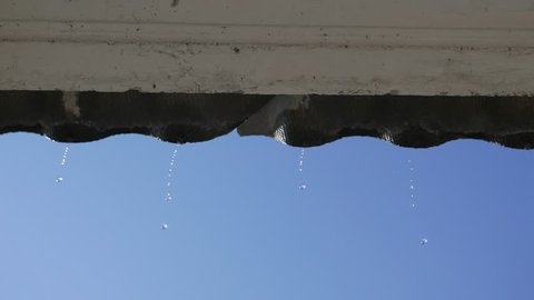 Raindrops dripping from the roof. Clear blue sky is the background. View of the open window. Banal plot. Tranquility and relaxation.