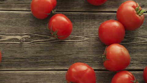 Tomatoes roll over the screen in slow motion on wooden background. HD