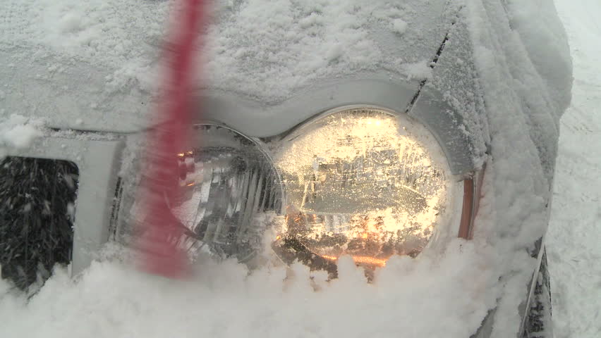 Brushing the snow off a car headlight