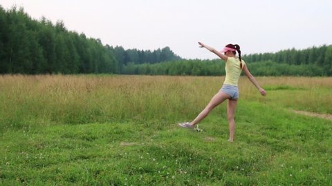 Girl does exercise somersault on meadow at summer evening
