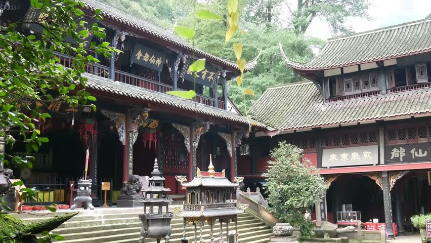 Qingcheng mountain Chengdu, place of founding of Chinese Taoism - temple courtyard with offering tables, entrance to hall of worship with hanging green creeper foliage & mountain trees behind temple