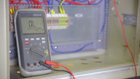Electrician testing electrical power. Industrial factory electrician testing voltage using multimeter at the electrical shield.