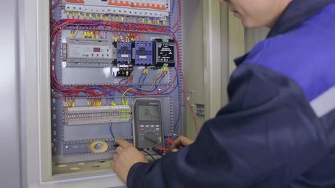 Electrician testing electrical power. Industrial factory electrician testing voltage using multimeter at the electrical shield.