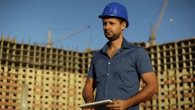 Architect with a tablet on a background of a under construction house. Engineer looking at tablet. Construction, foreman  worker with tablet computer.  Man builder with tablet computer.  - Powered by Shutterstock - Get 15% off with code: PIKWIZARD15