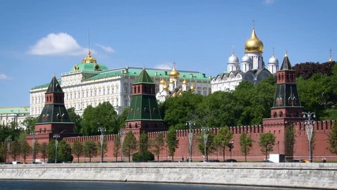Moscow City Historical Place. Big Kremlin Palace. Red Brick Wall, Towers. Christian Church. Green Foliage. Concrete Embankment. Blue Summer Sky.