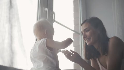 A Portrait of happy young mother with a baby at home kissing and laughing
