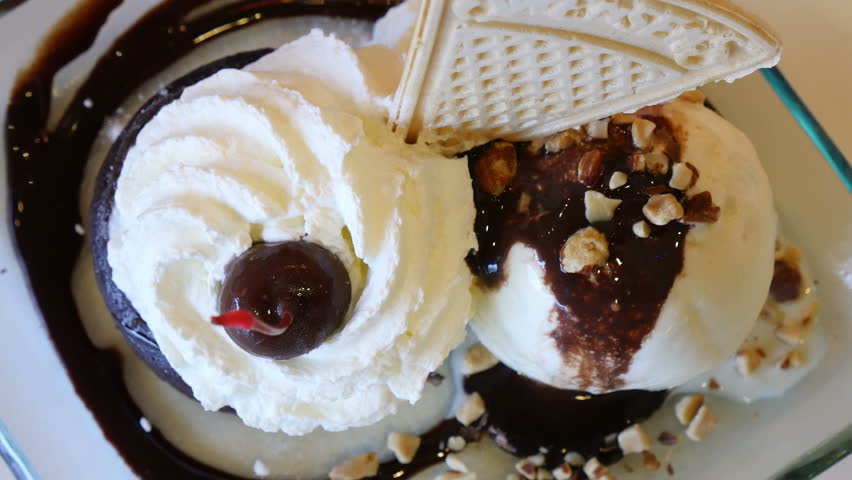 Women hand pick up cherry from the top of wiping cream of ice-cream chocolate lava. Close up scene.