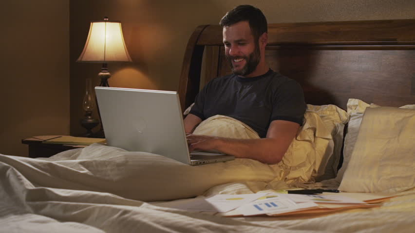 man works on laptop computer in bed
