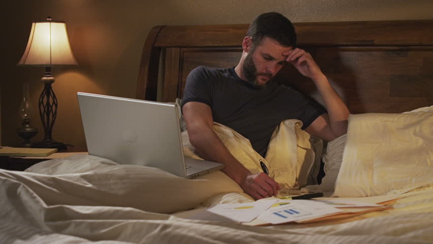 couple in bed. man works on laptop computer in bed.
