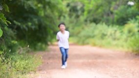 Two young Thai boy run together on the crack road in the natural park.